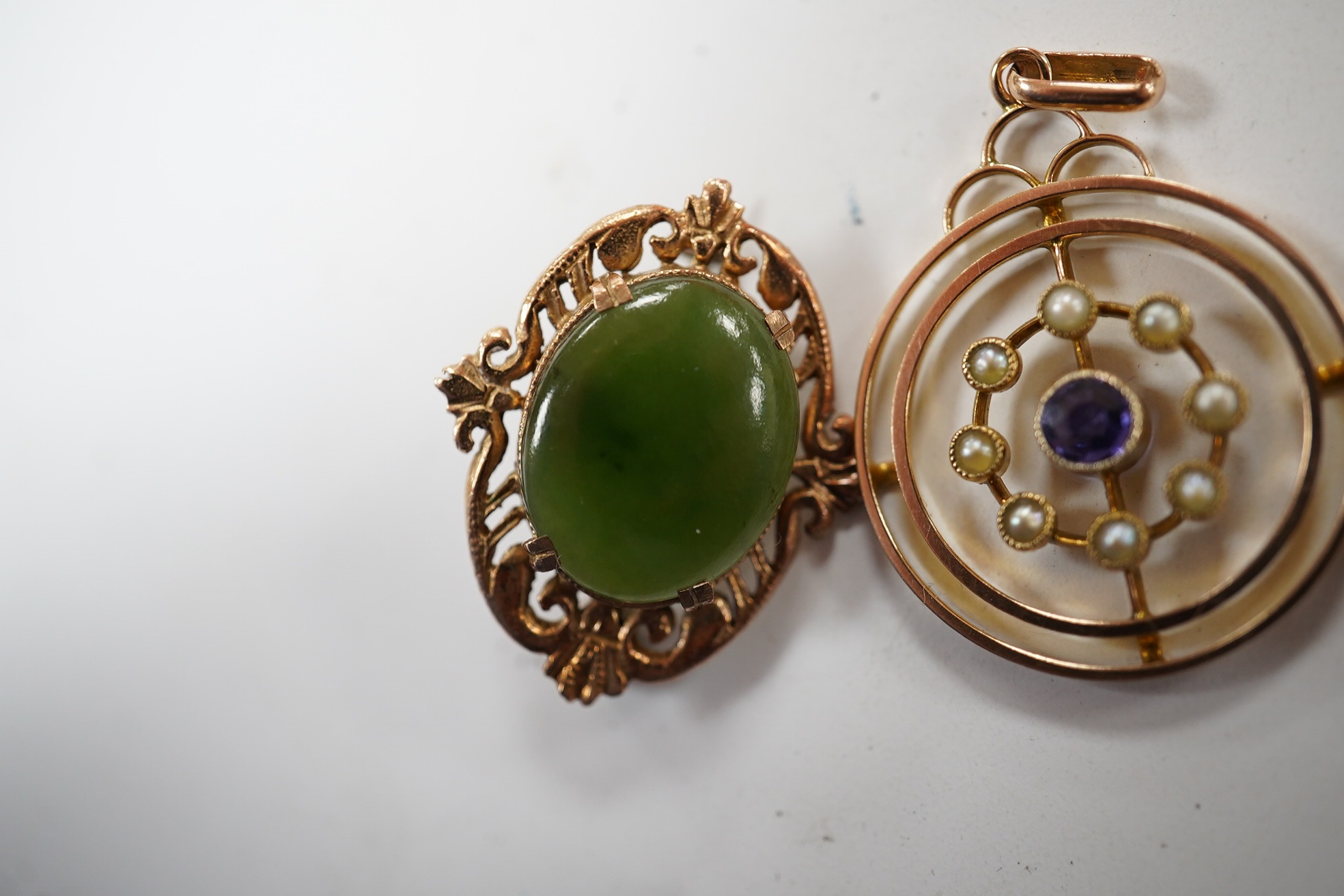 An Edwardian 9ct, sapphire and seed pearl cluster set open work circular pendant, 26mm, together with a similar 9ct, amethyst and seed pearl set brooch and a 9ct and nephrite set brooch, gross weight 7.4 grams. Condition